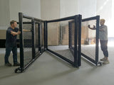 Cage MMA pliable en cours de repli, deux personnes rabattant les trains de panneaux