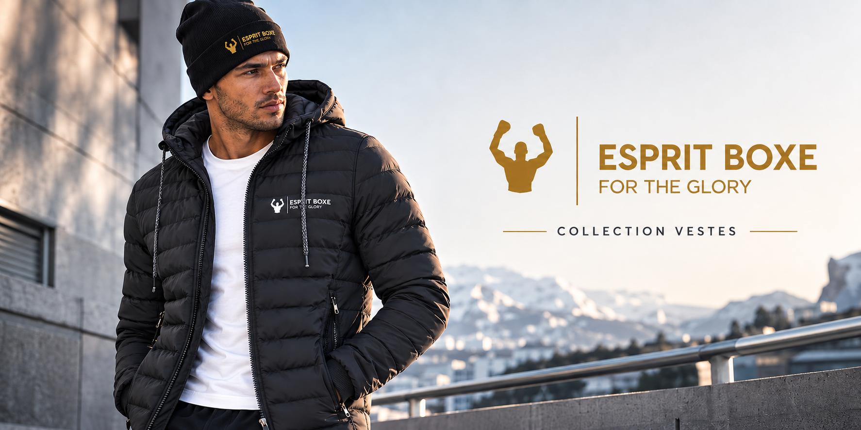 Collection vestes de boxe Esprit Boxe : homme en doudoune noire matelassée à capuche, logo blanc For the Glory sur la poitrine, t-shirt blanc et bonnet noir à logo doré, en extérieur devant des montagnes enneigées