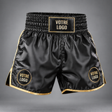 Short de boxe personnalisé en satin noir à passepoils dorés, panneau logo sur la ceinture et pastille logo sur chaque jambe