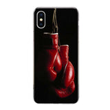 Coque iPhone à gants de boxe rouges suspendus par les lacets sur fond noir en clair-obscur
